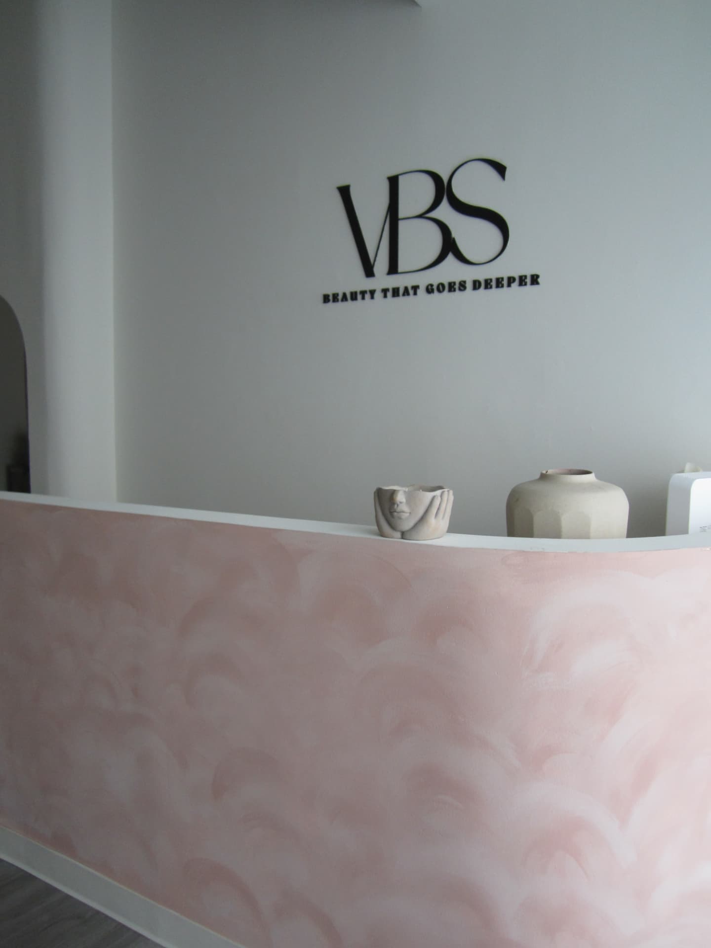 Vivre Beauty Studio logo wall above the front desk